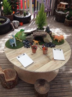 a wooden table topped with lots of plants and animals on top of grass covered ground