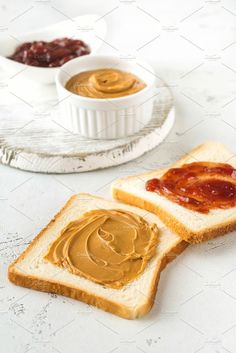 peanut butter and jelly sandwich on white bread with bowl of jelly in the back ground