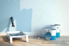 a blue wall with some paint cans next to it and a brush on the floor