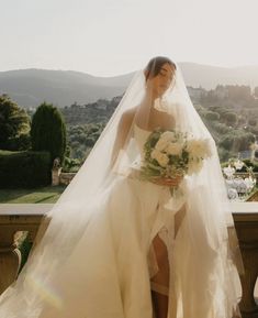 a woman in a wedding dress standing on a balcony