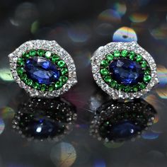 A ladies pair of 18 karat white gold Indigo earrings by Vivaan containing 2 oval cut blue sapphires having a total weight of 1.16 carats, 32 round green tsavorite garnets having a total weight of .35 carats, and 50 round diamonds having a total weight of .34 carats. Formal Tsavorite Earrings Fine Jewelry, Tsavorite Earrings For Anniversary In Fine Jewelry Style, Multi-stone Emerald Earrings For Gift, Emerald Multi-stone Earrings For Gift, Green Emerald Multi-stone Earrings, Tsavorite Gemstone Earrings For May Birthstone, Green Multi-stone Earrings For Anniversary, Indigo Earrings, Judith Leiber Couture