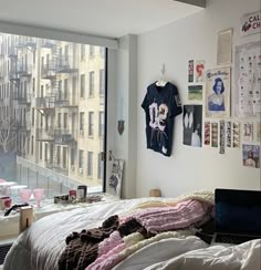 an unmade bed in front of a window with pictures on the wall above it