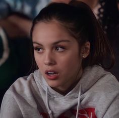 a girl in a grey hoodie is looking at the camera with an angry look on her face