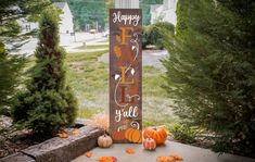 a wooden sign that says happy hall y'all with pumpkins on the ground