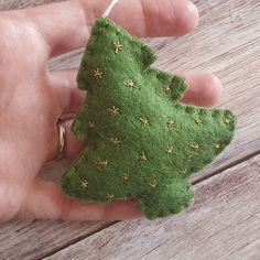 a hand holding a small green christmas tree ornament