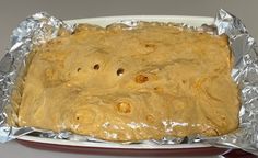 a pan filled with food sitting on top of aluminum foil next to a red plate