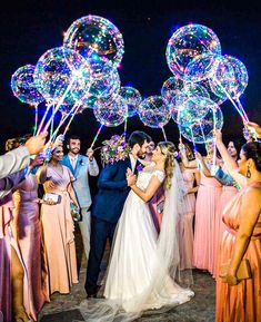 a bride and groom kissing in front of their wedding party with bubbles on the ground