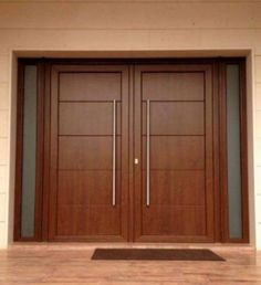 two wooden doors with metal handles in front of a white wall and wood flooring