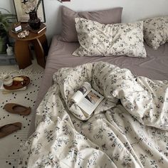 an unmade bed with a book on it and slippers scattered around the bed