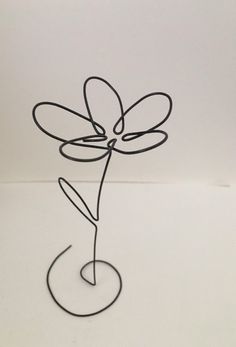 a wire sculpture of a flower on a white surface with a black circle around it