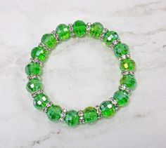 Pretty green color glass beaded stretch bracelet with crystal spacer beads. Each bead is round and all facet cut with a slight aurora borealis finish.  A nice green color fashion piece that is great everyday or for any occasion.   Stretch Bracelet The glass beads are 10 mm  Silver plated crystal spacer beads. Length is 7.5 inches Cheap Green Beaded Bracelets With Oval Beads, Green Stretch Bracelet With Faceted Round Beads, Green Round Beads Stretch Bracelet For Party, Green Stretch Bracelet With Round Beads For Party, Green Rondelle Beaded Bracelets With Faceted Beads, Green Crystal Round Bracelet For Parties, Green Round Crystal Bracelet For Party, Faceted Green Beaded Bracelets, Green Crystal Bracelet With Round Beads