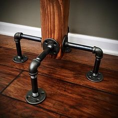 two metal pipes are on the floor near a wooden post and some wood planks