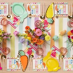 there are many colorful plates and utensils on the table with flowers in them