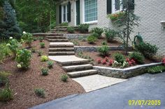 a house with steps leading up to the front door and landscaping around it, along with flowers