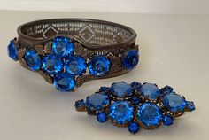 "Art Deco blue rhinestone Czech bracelet and brooch. Unmarked.  1920-s  brooch -  2 1/8\" x 1 1/8\" , simple \" C \" clasp  bracelet - approximately 6 7/8\" x  1 1/4\" w. ( Photo: my wrist - 6.75\" )  Very good condition  00954 11/09/22" Antique Blue Jewelry With Brooch, Blue Art Deco Formal Brooch, Vintage Sapphire Brooch Jewelry, Ornate Blue Brooches For Wedding, Ornate Blue Wedding Brooches, Formal Blue Costume Jewelry Bracelets, Blue Costume Jewelry Bracelets For Formal Occasions, Antique Blue Bracelet Jewelry, Antique Blue Round Bracelets