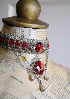 This majestic elizabethan inspired choker is made in a very lush combination of antique gold and red tones. It is embellished with two deep red faceted crystal cabochons as well as beautiful glass faux pearls. A variety of different antique bronze filigree pieces adorn both the front and the back. Measurements : 1 inch (2.5 cm) wide, 11.5 inches (29 cm) when completely closed, adjustable with 10 cm chain extension. This item is sent packaged securely and sent out with DHL Express, delivered in 2 Red Gothic Choker For Festivals, Vintage Costume Necklaces For Halloween, Vintage Halloween Costume Necklaces, Handmade Red Vintage Choker, Elizabethan Jewelry, Vampire Choker, Mad Hatter Top Hat, Victorian Gothic Jewelry, Tudor Costumes