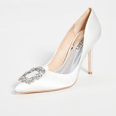 a pair of white high heeled shoes with a crystal buckle on the toe and an embellished shoe clip