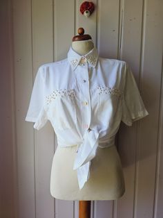 Charming blouse with pearl embroidery in off-white In perfect condition, buttons show some slight signs of wear. 70% Viscose 30% polyester Signed with Gr.38 Seen on a size 38 Laying Flat Dimensions: Shoulder width: 44 cm/ 17.32 inches Armpit-armpit: 51 cm/ 20.07 inch Back length: 68 cm/ 26.77 inch Feminine Short Sleeve Cream Blouse, Feminine Cream Short Sleeve Blouse, Workwear Embroidered Short Sleeve Blouse, Short Sleeve Embroidered Shirt For Work, Embroidered Short Sleeve Workwear Blouse, Feminine Short Sleeve Shirt With Buttons, Elegant Short Sleeve Embroidered Shirt, Feminine Fitted Short Sleeve Shirt, Formal Short Sleeve Embroidered Blouse