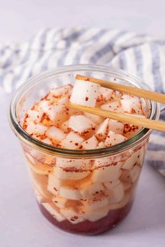 a jar filled with food and two wooden chopsticks sticking out of the top