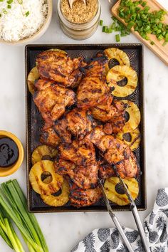 grilled chicken with pineapple slices and onions on a tray next to other ingredients