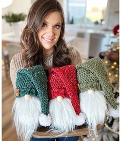 a woman holding three knitted christmas stockings