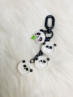 three panda bear key chains on a white fur surface