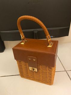 a brown wicker bag sitting on top of a white tile floor next to a tv