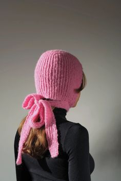 a woman wearing a pink knitted hat with a large bow on the back of her head