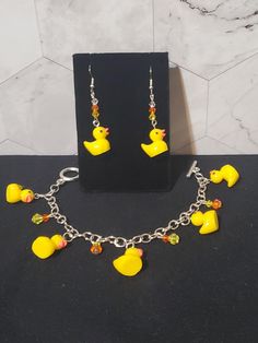 a necklace and earring set with yellow rubber ducky charms on a black background