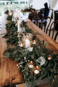 a long wooden table topped with candles and greenery