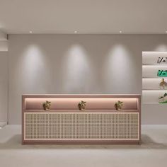 an empty room with white walls and plants on the wall, in front of a pink bench