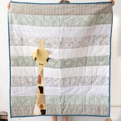 a giraffe standing next to a large quilt