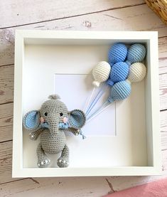 an elephant in a box with balloons attached to the wall next to a basket filled with blue and white crocheted balls