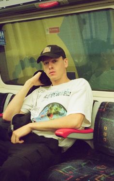 a young man sitting on a subway train with his head propped up against the seat