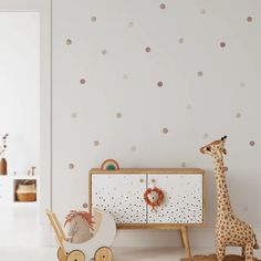 a baby's room with polka dot wallpaper and a toy giraffe