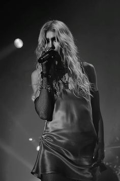 a woman with long hair wearing a black dress and holding a microphone in her hand