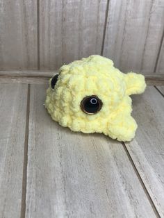 a small yellow stuffed animal sitting on top of a wooden floor