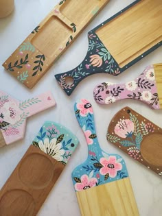 wooden utensils and spoons are laid out on a white counter top with floral designs