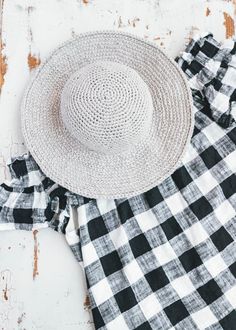 a white hat sitting on top of a black and white checkered dress next to a straw hat