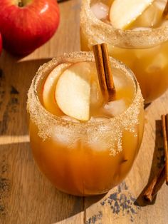 two glasses filled with apple cider on top of a wooden table