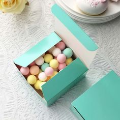 a box filled with small pastel colored candies on top of a white table