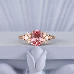 a pink diamond ring sitting on top of a white cloth