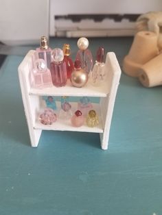 there is a small shelf with perfumes on it and some other things in the background