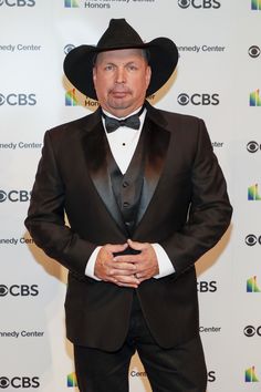 a man in a suit and hat standing on a red carpet with his hands behind his back