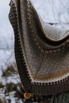 a man wearing a brown and white knitted shawl over his shoulder in the snow