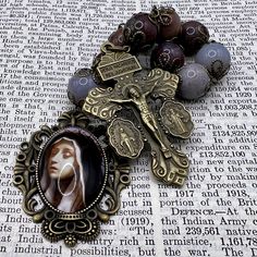 This single-decade rosary, handmade in Scotland, is a striking piece that combines deep spiritual symbolism with an elegant design. The beads are made from large 12mm dusk purple agate, giving the rosary a rich, mysterious appearance. The metalwork, crafted from antiqued brass, enhances the vintage Victorian Gothic feel, making it a unique and captivating devotional item. The rosary features a detailed Pardon Crucifix, which includes inscriptions of powerful prayers. The Pardon Crucifix is deepl Spiritual Gemstone Beads Rosary, Bohemian Rosary With Natural Stones For Gifts, Spiritual Crucifix Jewelry With 8mm Beads, Spiritual Rosary With Natural Stones As Gift, Handmade Spiritual Healing Rosary, Bohemian Cross Rosary Bracelet Gift, Spiritual Beaded Rosary Bracelet With Crucifix, Spiritual Beaded Rosary For Jewelry Making, Spiritual Hand-strung Cross Jewelry