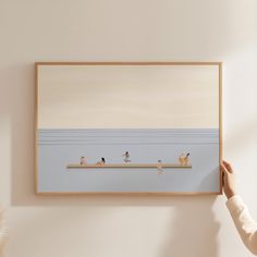 a person holding up a painting with people on the beach in water and birds flying around