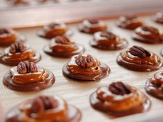 chocolate covered donuts with pecans and caramel toppings on a baking sheet