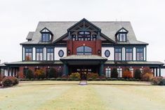 a large red brick house with lots of windows on it's front porch and lawn