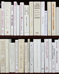 several books are stacked on top of each other in a bookcase, one is white and the other is black